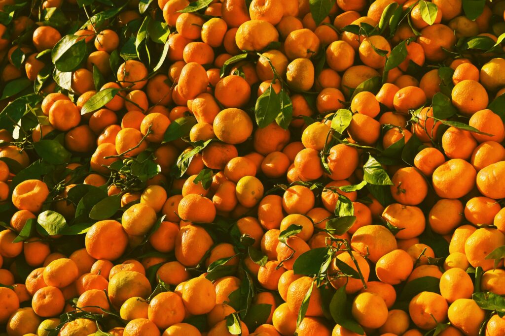 A vibrant display of fresh tangerines with leaves at an open-air market. Perfect depiction of citrus abundance.